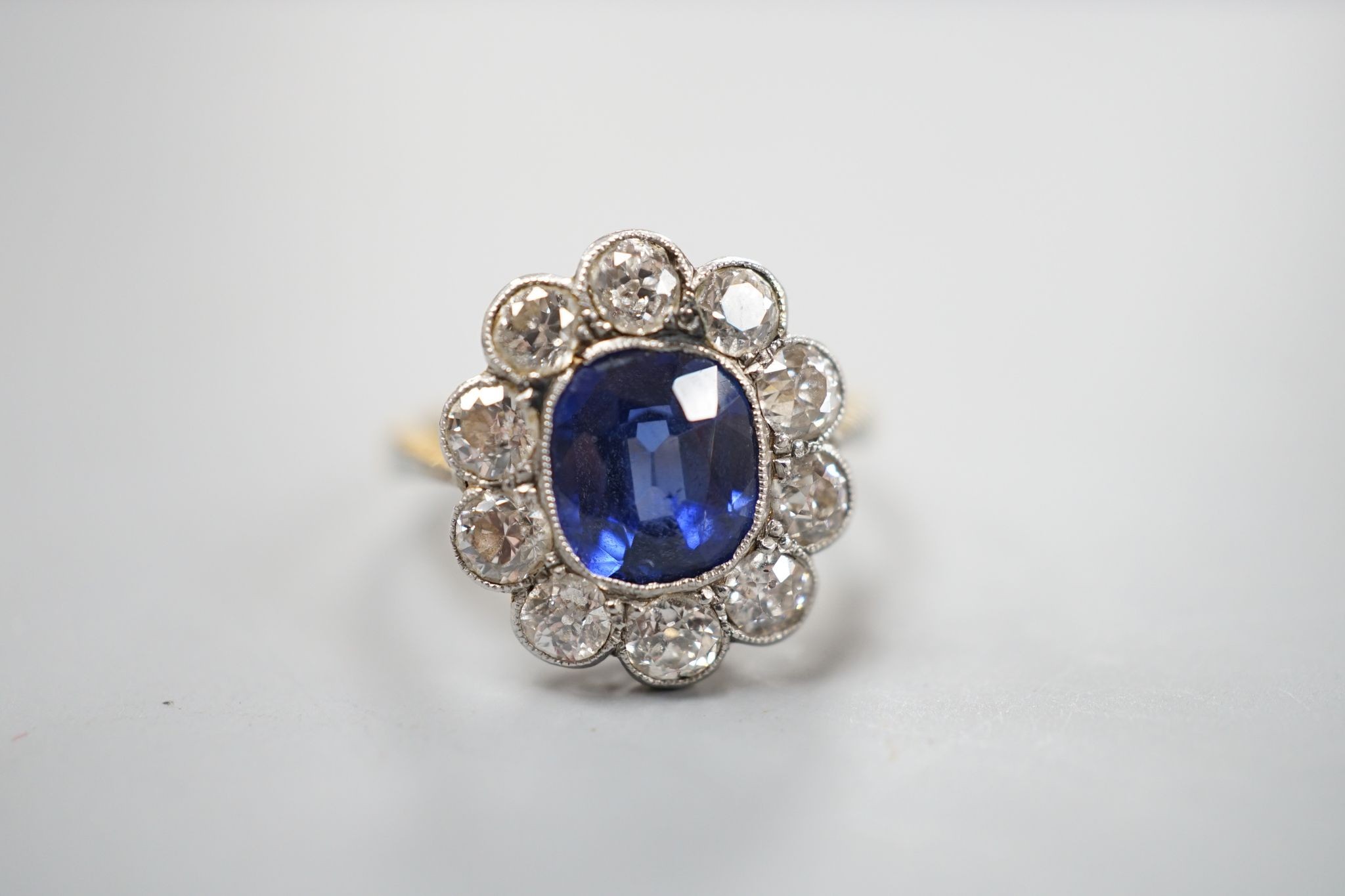An 18ct gold and platinum, synthetic sapphire and diamond set oval cluster ring